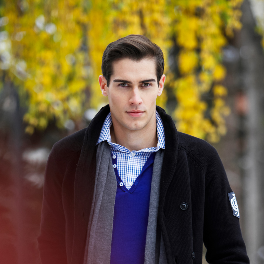 A fashionable man walks outside on a fall day.
