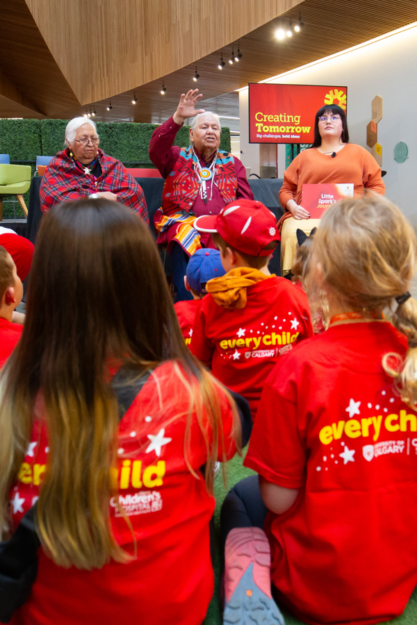 An Indigenous elder reads a story to a group of children.