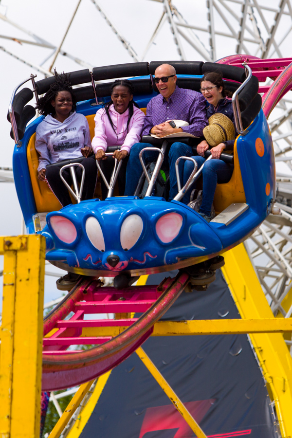 A senior and three girls scream while riding a rollercoaster.