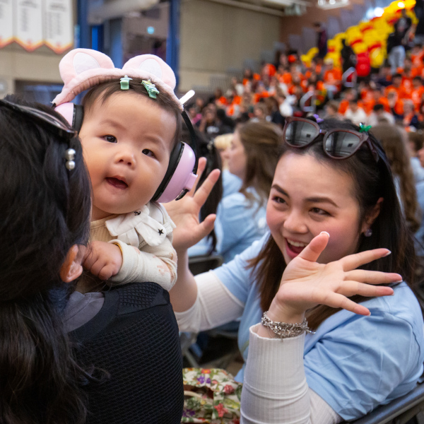 A mature student smiles at her baby during a pep rally.