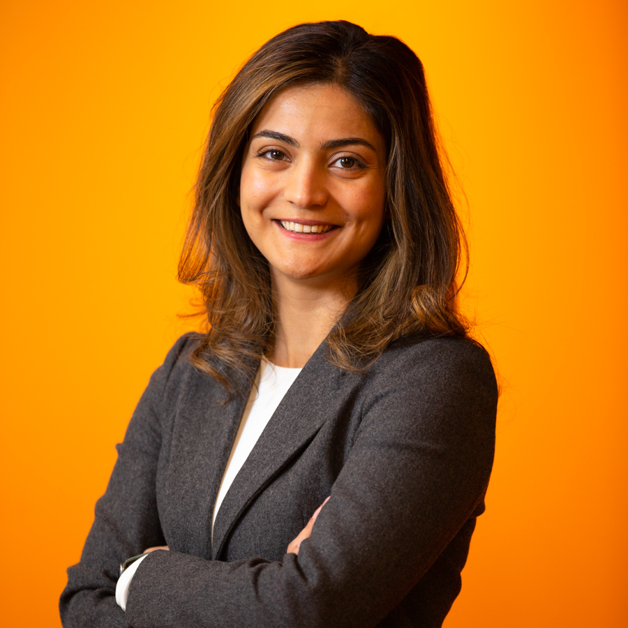 A female professional poses in front of an orange background.