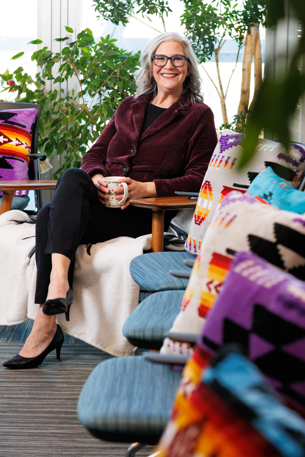 A female professor sits and holds a tea cup.