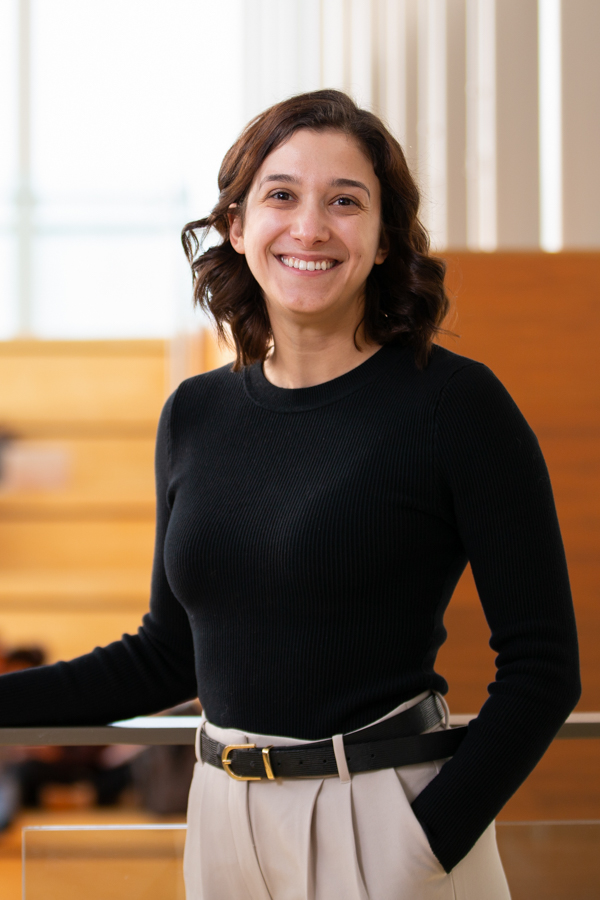 A woman dressed business casual stands in a professional building.